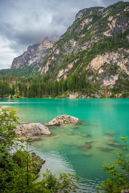 Le lac de Braies entouré de forêts de pins et des chaînes rocheuses des Dolomites par une journée nuageuse en Italie