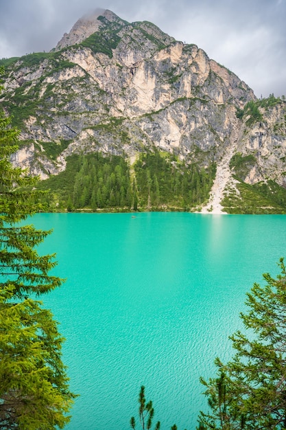 Le lac de Braies entouré de forêts de pins et des chaînes rocheuses des Dolomites par une journée nuageuse en Italie