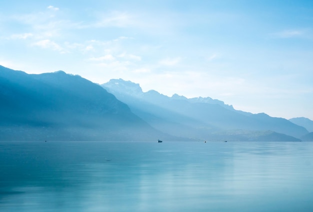 Lac avec une chaîne de montagnes en arrière-plan contre un ciel nuageux