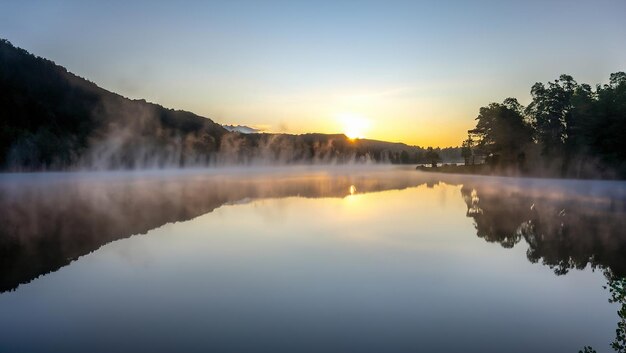 Un lac avec un ciel brumeux et le soleil se levant derrière