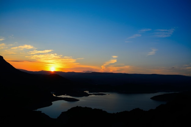 Lac et collines sous un ciel coloré au coucher du soleil Italie