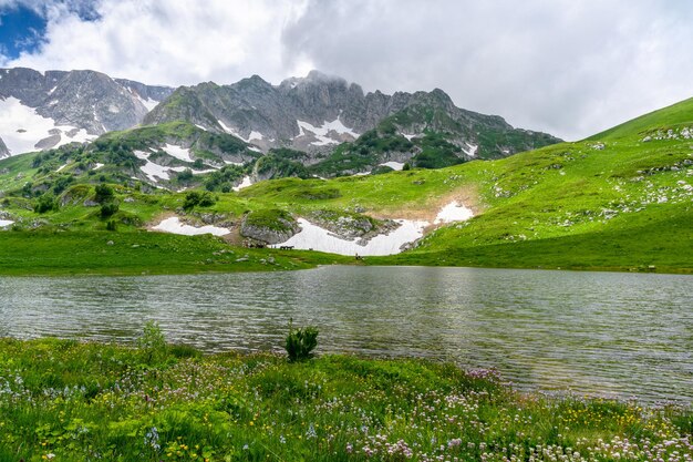 Photo lac dans les montagnes alpines avec des montagnes de prairies vertes au printemps