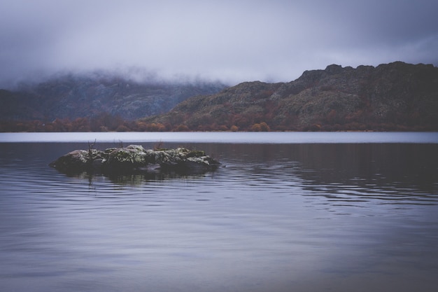 Photo lac entre les montagnes avec des nuages bas