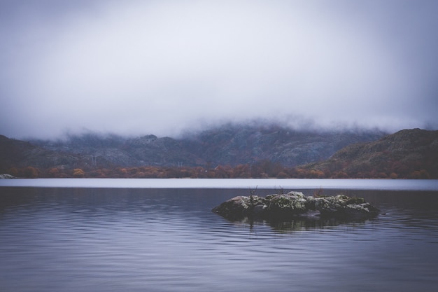 Photo lac entre les montagnes avec des nuages bas