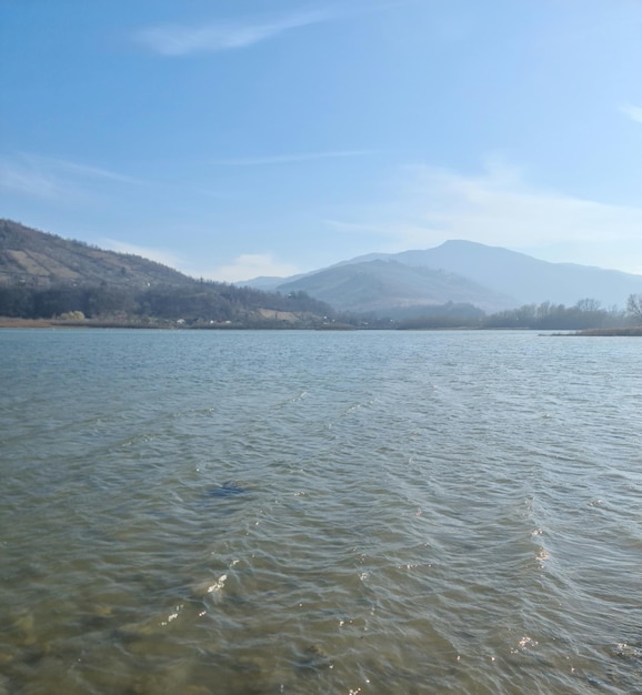 Un lac avec une montagne en arrière-plan et un ciel bleu avec des nuages