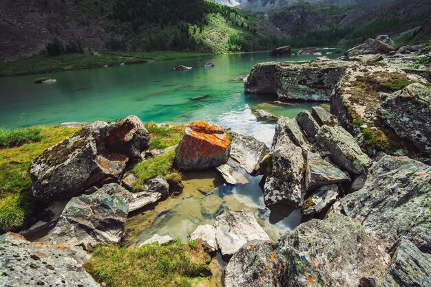 Le lac de montagne est entouré de grosses pierres et de rochers avec de la mousse