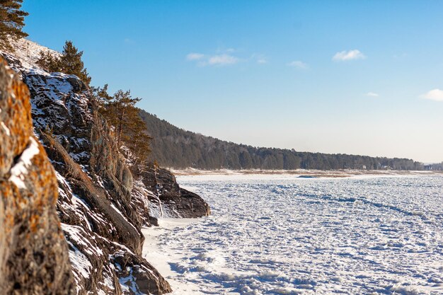 Un lac ou une rivière gelée en hiver. Près de la forêt et des montagnes sous la neige. paysages d'hiver