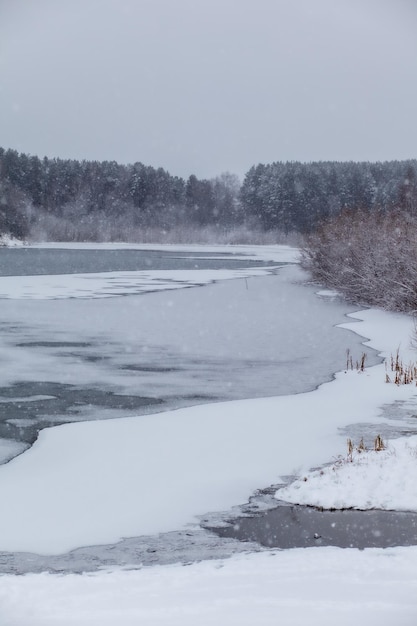 Un lac ou une rivière gelés en hiver. Près de la forêt et des montagnes sous la neige. Beaux paysages d'hiver. Voyages d'hiver dans la nature.