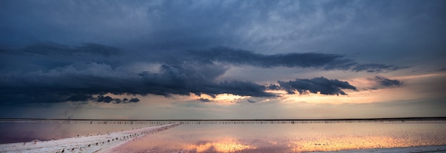lac rose et plage de sable avec une baie de la mer sous un ciel bleu avec des nuages