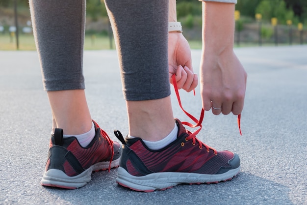 Laçage des chaussures de course. Gros plan des mains de femme qui lacent des formateurs à l'extérieur dans un parc