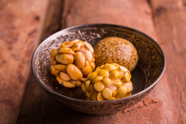 Laddoo sain utilisant des arachides grillées, du sésame et du daliya fendu avec du jaggery, servi dans une assiette en bois, mise au point sélective