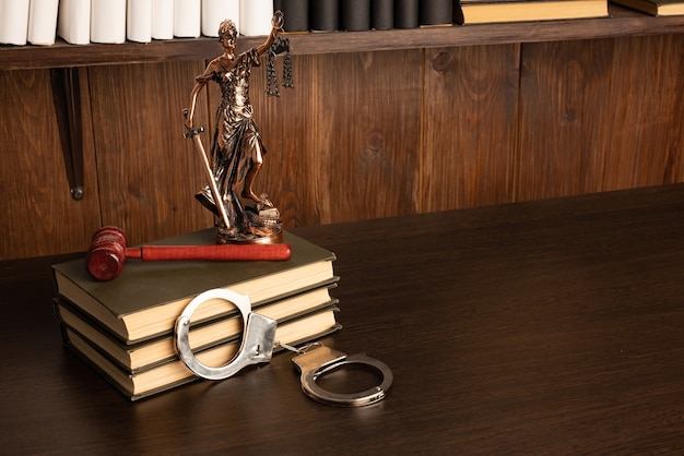 Lady Justice, marteau du juge, livres, menottes sur une vieille table en bois