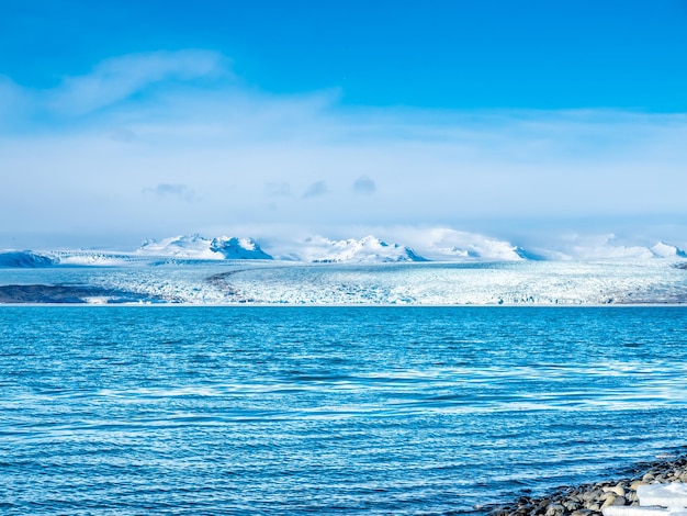 Lagune d'iceberg de Jokulsarlon avec glacier et grand iceberg sous un ciel bleu nuageux en Islande