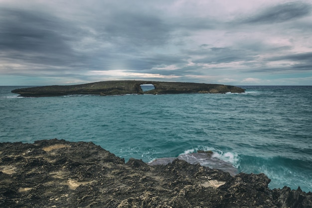 Laie point vue mer du rocher avec un trou avant le coucher du soleil avec un ciel gris foncé