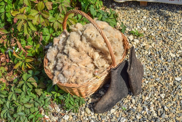 La laine dans le panier et les bottes noires tondées de laine de mouton