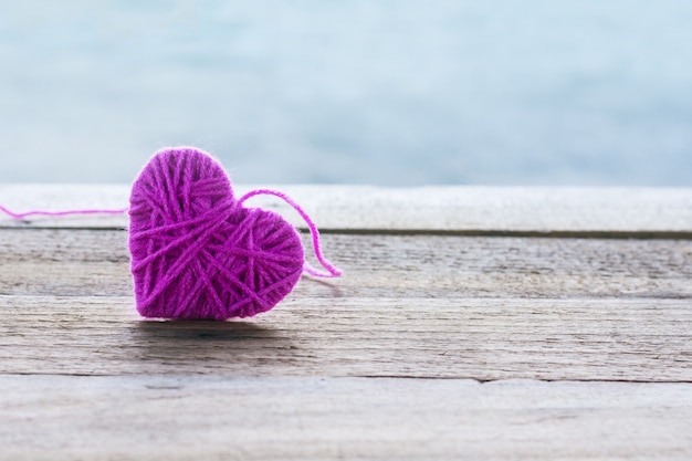 Photo laine à tricoter rose en forme de coeur sur bois vintage