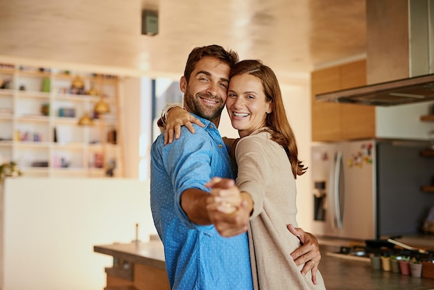 Laissez l'amour mener Portrait recadré d'un jeune couple affectueux dansant dans leur cuisine