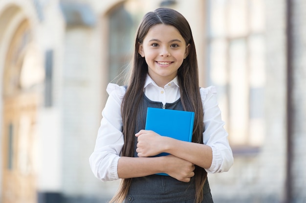 Laissez parler le livre. Un enfant heureux tient un livre de bibliothèque. Bibliothèque de l'école. Lecteur de bibliothèque à l'extérieur. Rat de bibliothèque mignon retour à l'école. L'éducation formelle. Journée du savoir. Bibliopole. Librairie. 1er septembre.