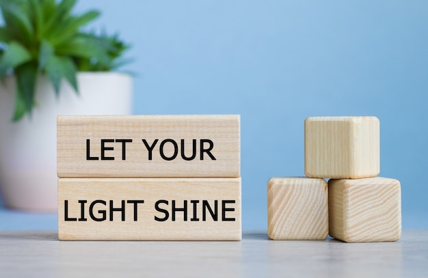 Photo laissez votre lumière briller le mot sur des cubes en bois sur un bureau blanc.