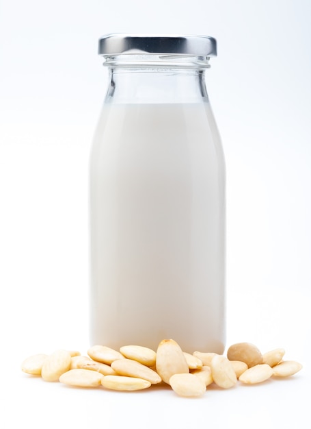 Lait d'amande en bouteille de verre. Comprend les amandes pelées. Isolé