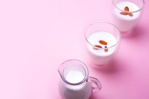 Lait d'amande dans une carafe et deux verres sur fond rose Espace vide pour le texte