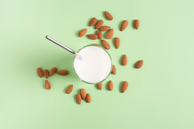 Lait d'amande dans un verre avec une paille, sur un vert clair