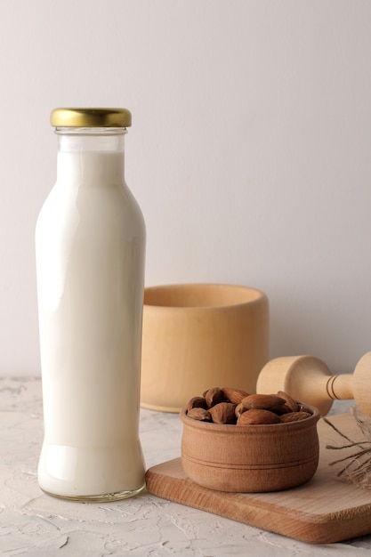 Lait d'amande frais dans une bouteille en verre et noix d'amande sur fond clair