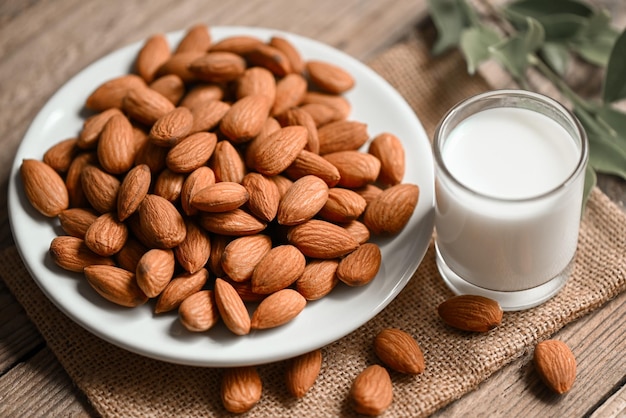 Lait d'amande et noix d'amandes sur fond de plaque blanche Délicieuses amandes douces sur la table Noix d'amandes grillées pour des aliments sains et des collations