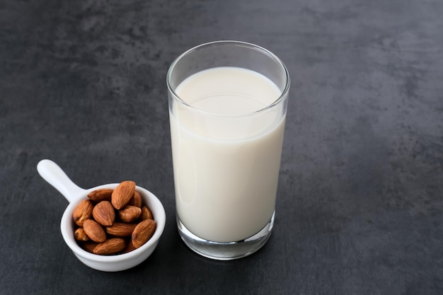 Lait d'amande en verre avec des amandes sur fond sombre Espace pour le texte