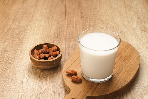 Lait d'amande en verre avec amandes sur table en bois. Espace pour le texte