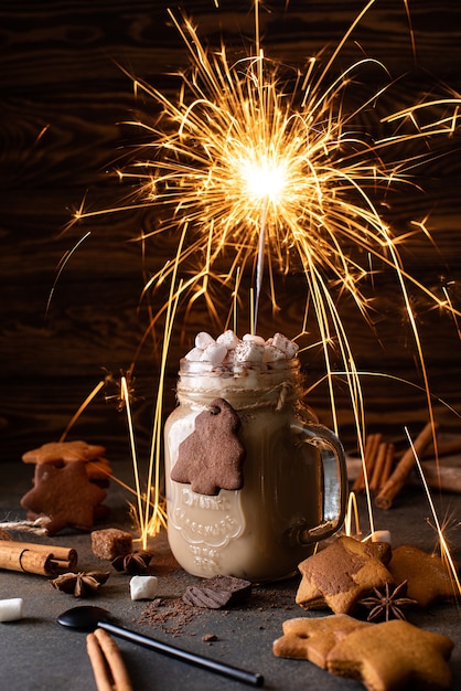 Lait au chocolat au chocolat, cannelle et guimauve avec sparkler sur une table en bois