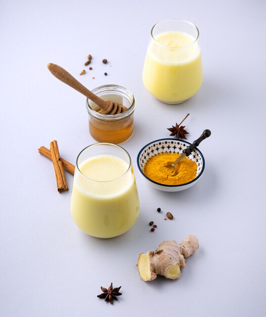 Lait aux épices de curcuma et miel sur fond gris