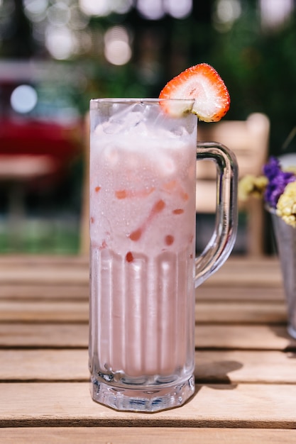 Lait aux fraises glacées servi avec des tranches de fraise.