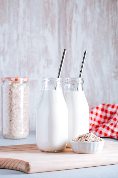 Lait d'avoine non laitier dans des bocaux en verre avec des pailles métalliques réutilisables. Alternative au lait végétalien sain nature morte, espace de copie. Substitut du lait de vache traditionnel avec des flocons d'avoine, concept de mode de vie sain