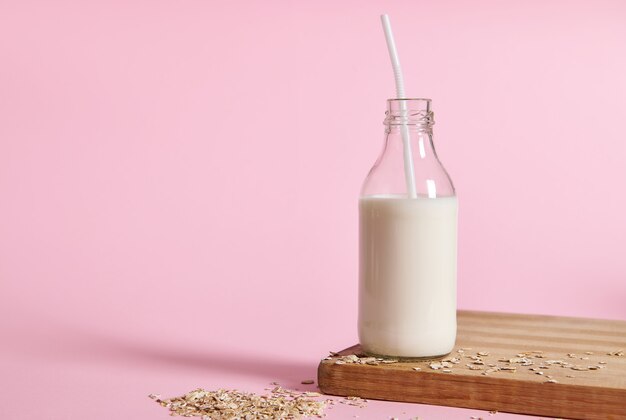 Lait d'avoine végétalien sur planche de bois et flocons d'avoine éparpillés