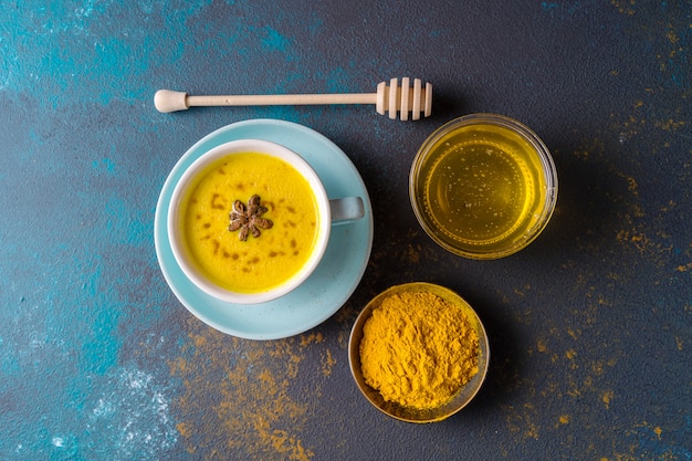 Lait ayurvédique au curcuma doré au curcuma et autres épices sur fond bleu. Mise à plat.