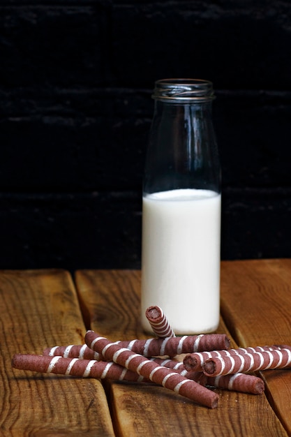 Lait avec un biscuit dans une bouteille en verre sur un fond en bois