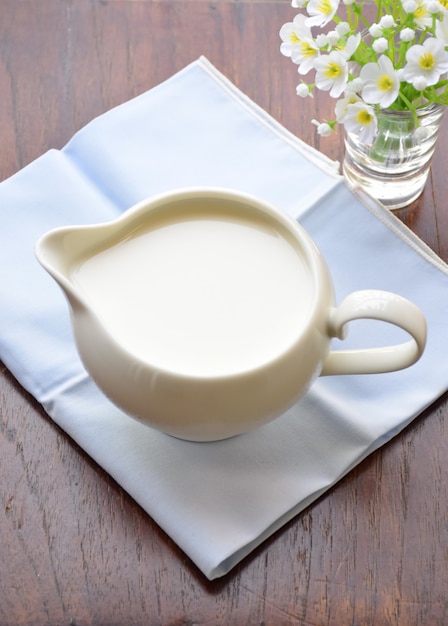 Photo lait blanc en pot sur la table en bois