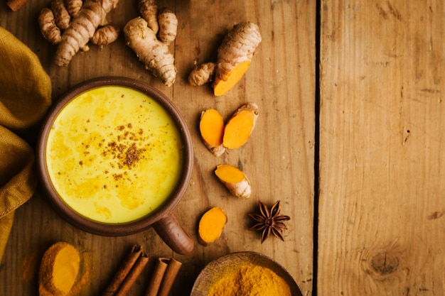 Lait chaud au curcuma avec des épices sur une table en bois