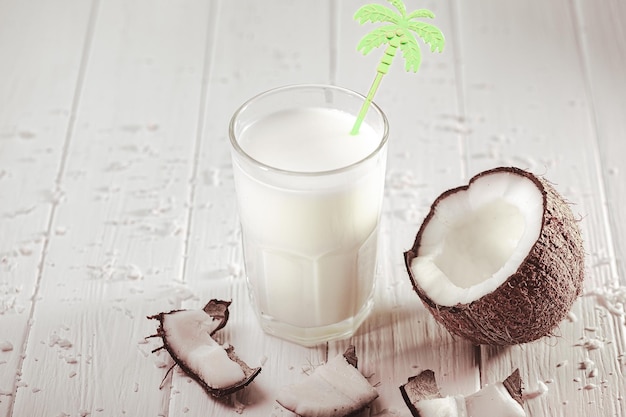 Lait de coco en verre avec des fruits de noix de coco sur une table en bois Concept de lait alternatif Boisson tropicale