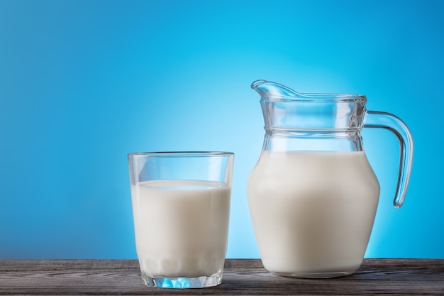 Lait dans un verre et une cruche sur une table en bois