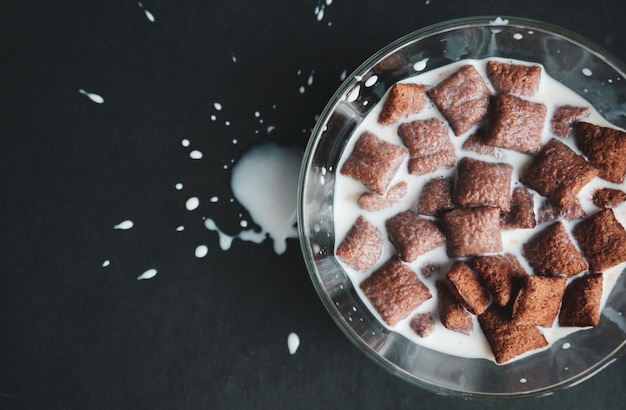 Le lait du sac est versé dans un bol transparent avec des pastilles de chocolat pour le petit-déjeuner