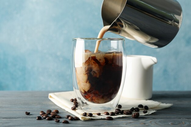 Le Lait Est Versé Dans Un Verre De Café. Composition Avec Café Glacé