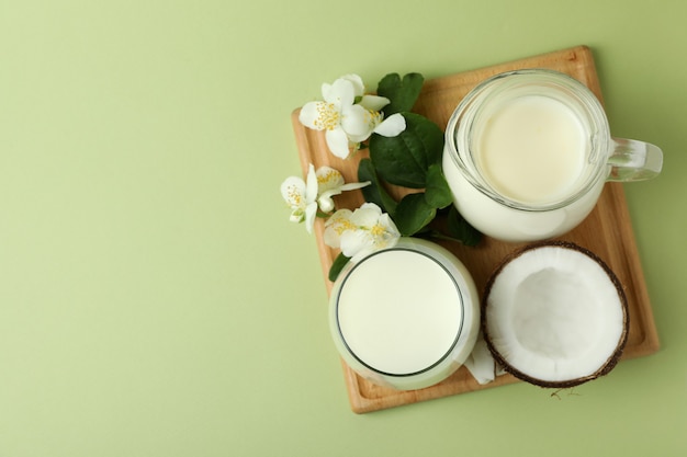 Lait, fleurs et noix de coco à bord sur fond vert