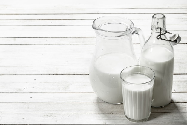 Lait frais dans une cruche sur une table en bois blanche.