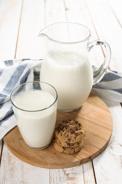 Lait frais en pichet et verre sur bois