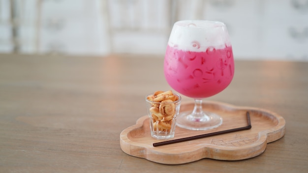 Le lait glacé à la fraise dans le verre sert de petits biscuits sur la table en bois