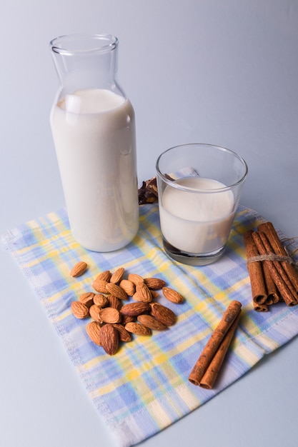 Le lait naturel dans des bouteilles avec des noix d&#39;amande et des bâtons de cannelle sur la serviette, sur fond blanc.