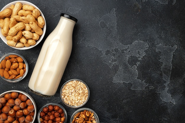 Lait de noix végétalien non laitier et des tas de différentes noix vue de dessus sur un bureau en bois