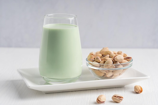 Lait de pistache à base de plantes végétariennes non laitières servi dans du verre sur une assiette avec un bol de graines sur la table